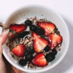 Muesli - Person Holding Bowl of Grape and Sliced Strawberries