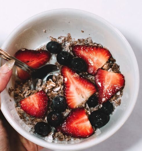 Muesli - Person Holding Bowl of Grape and Sliced Strawberries