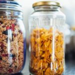 Muesli - Glass jars with healthy cornflakes and muesli placed on table in kitchen