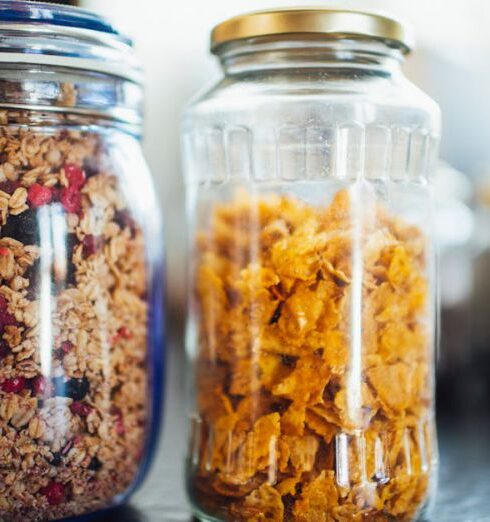 Muesli - Glass jars with healthy cornflakes and muesli placed on table in kitchen