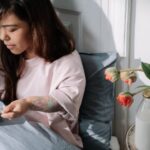 Muesli - Woman eating cereal with milk sitting in a bed