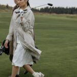 Tee - Woman in White Coat Holding Black Dslr Camera on Green Grass Field