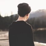 Beanie - Selective Focus Photography of Man Standing on Brown Soil Facing Body of Water