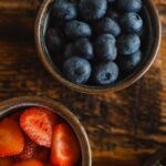 Healthy Eating - Two bowls of berries and a salad on a wooden table