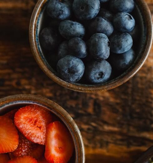 Healthy Eating - Two bowls of berries and a salad on a wooden table