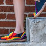 Stilettos - A woman in colorful shoes standing on a brick wall