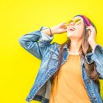 Jackets - Smiling Woman Looking Upright Standing Against Yellow Wall