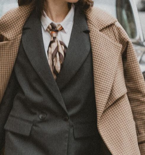 Outerwear - A woman in a suit and hat walking down the street with a suitcase