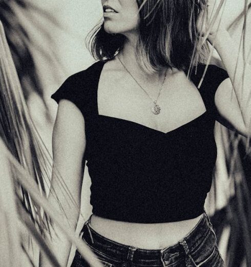 Tones - A woman in black shorts and top standing in front of palm trees