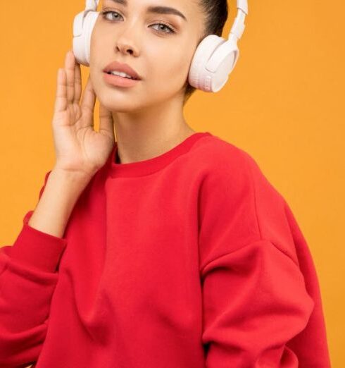 Trends - Woman in Red Sweatshirt and Blue Jeans Wearing White Headphones