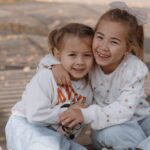 Sweaters - Two little girls sitting on a bench in the woods