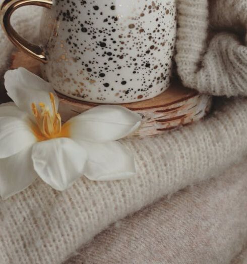 Cardigans - Cup of Coffee Standing on Pile of Cardigans Decorated with Flowers