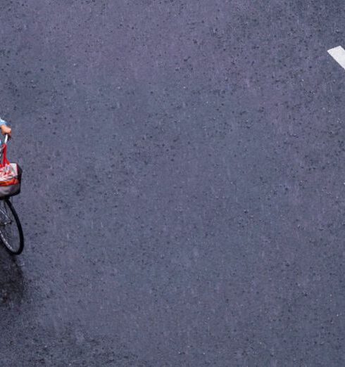 Windbreaker - Aerial view of a man with blue raincoat riding bicycle on a wet street of a rainy day at HCMC, Vietnam