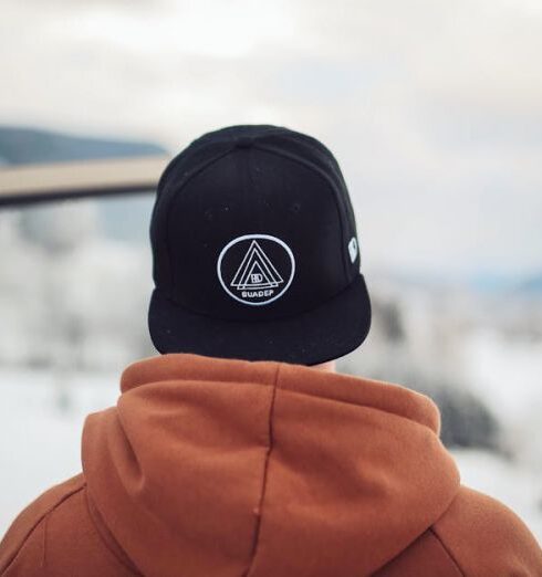 Caps - Person Wearing Black Cap and Orange Hoodie Turning His Back