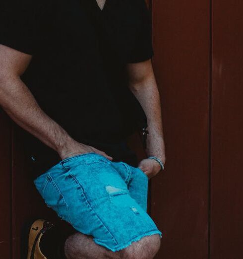 Shorts - Photo of Man Wearing Black T-Shirt Leaning on Wall