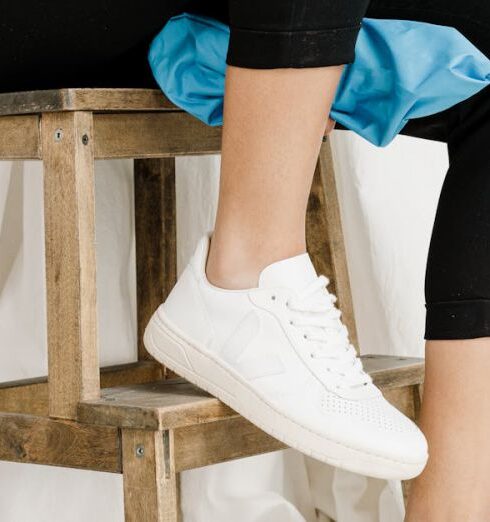 Leggings - Person in Black Leggings and White Sneakers Sitting on Brown Wooden Stool