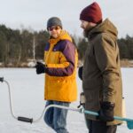 Jackets - Man in Brown Jacket and Red Knit Cap Holding Blue Stick