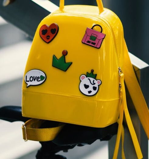 Bags - Yellow Backpack With Five Assorted Stickers on Grey Metal Stairway Rail