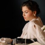 Clutch - Woman in White Long Sleeve Shirt Sitting by the Table