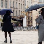 Coats - Two women walking in the rain with umbrellas