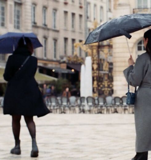 Coats - Two women walking in the rain with umbrellas