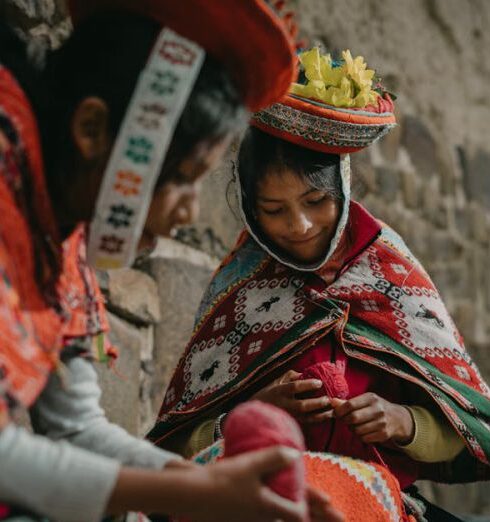 Capes - Peruvian Girls Wearing Traditional Clothing, Sitting by a Wall