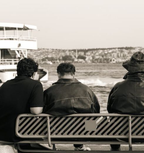 Jackets - Three men sitting on a bench watching a boat