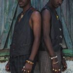 Vests - Two men standing next to each other in front of a window