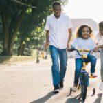 Family - Man Standing Beside His Wife Teaching Their Child How to Ride Bicycle