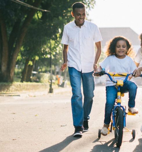 Family - Man Standing Beside His Wife Teaching Their Child How to Ride Bicycle