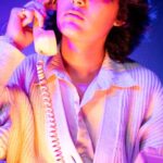 Cardigans - A young man sitting on a chair talking on a phone