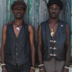 Vests - Two men stand in front of a blue window