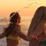 Bikinis - Women in Bikinis Holding Hands and Running on Sea Shore Together