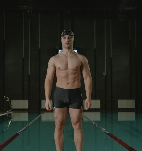 Swim Shorts - Topless Man in Black Shorts Holding Red and Black Stick