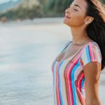 Swimsuit - Woman in a Multicolored Swimsuit Sitting on Beach