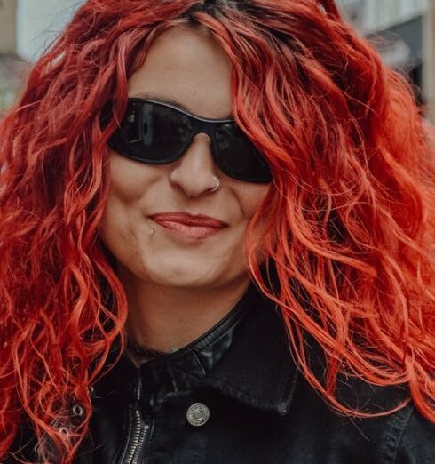 Jackets - A woman with red hair and sunglasses standing in a city