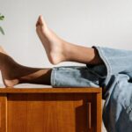 Jeans - Person in Blue Denim Jeans Lying on Brown Wooden Table