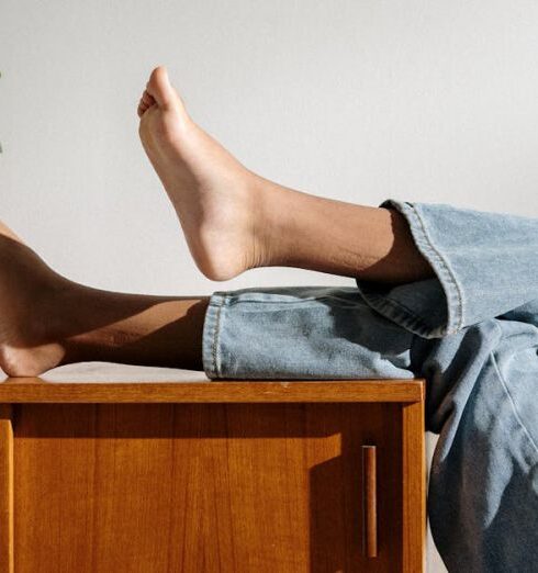 Jeans - Person in Blue Denim Jeans Lying on Brown Wooden Table