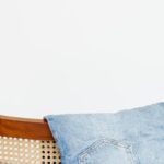 Jeans - Trendy blue jeans put on back of wooden chair near empty white wall