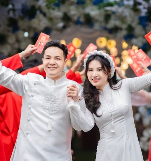 Tunics - Newlywed in Traditional Vietnamese White Ao Dai Among Wedding Guests in Red Tunics