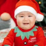 Rompers - A baby in a santa outfit sitting on the floor