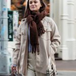 Streetwear Shops - Positive female walking with hand in pocket on sidewalk and carrying bags during shopping in city