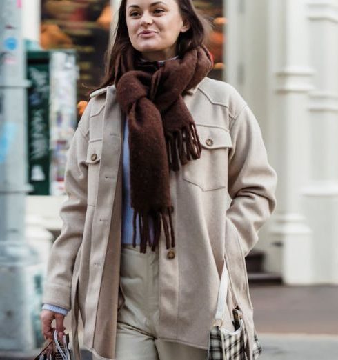 Streetwear Shops - Positive female walking with hand in pocket on sidewalk and carrying bags during shopping in city