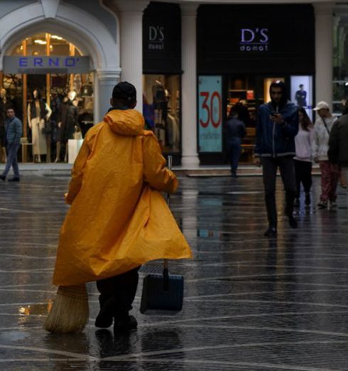 Fashion Stores - Man in a Raincoat Cleaning the Street