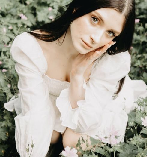 Clean Beauty - Woman in White Dress Crouching in Flowers