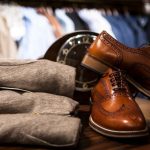 Footwear - Pair of Brown Leather Wingtip Shoes Beside Gray Apparel on Wooden Surface