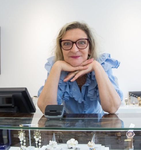 Luxury Watches - Woman in Blue Shirt Standing Behind the Counter