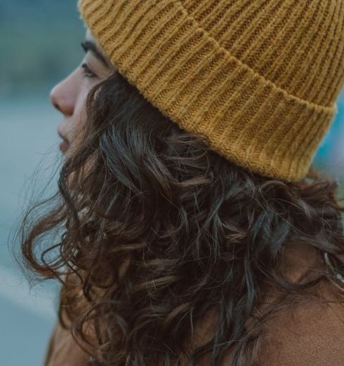 Outdoor Apparel - Young Woman in a Brown Coat and Yellow Hat Standing Outside