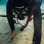 Scuba Diving Gear - Diver Placing a Measuring Tape Next to the Find for a Photo