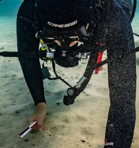 Scuba Diving Gear - Diver Placing a Measuring Tape Next to the Find for a Photo